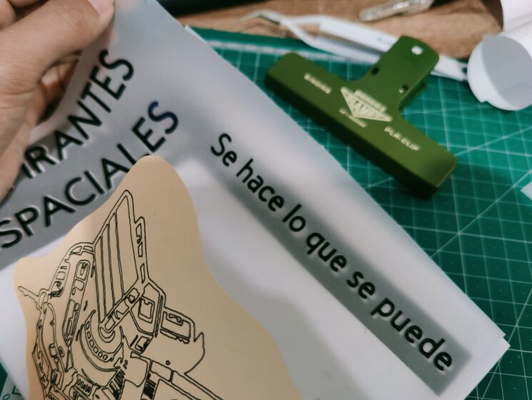 Mano sostiene un fanzine sin acaba con vinilos y varios materiales